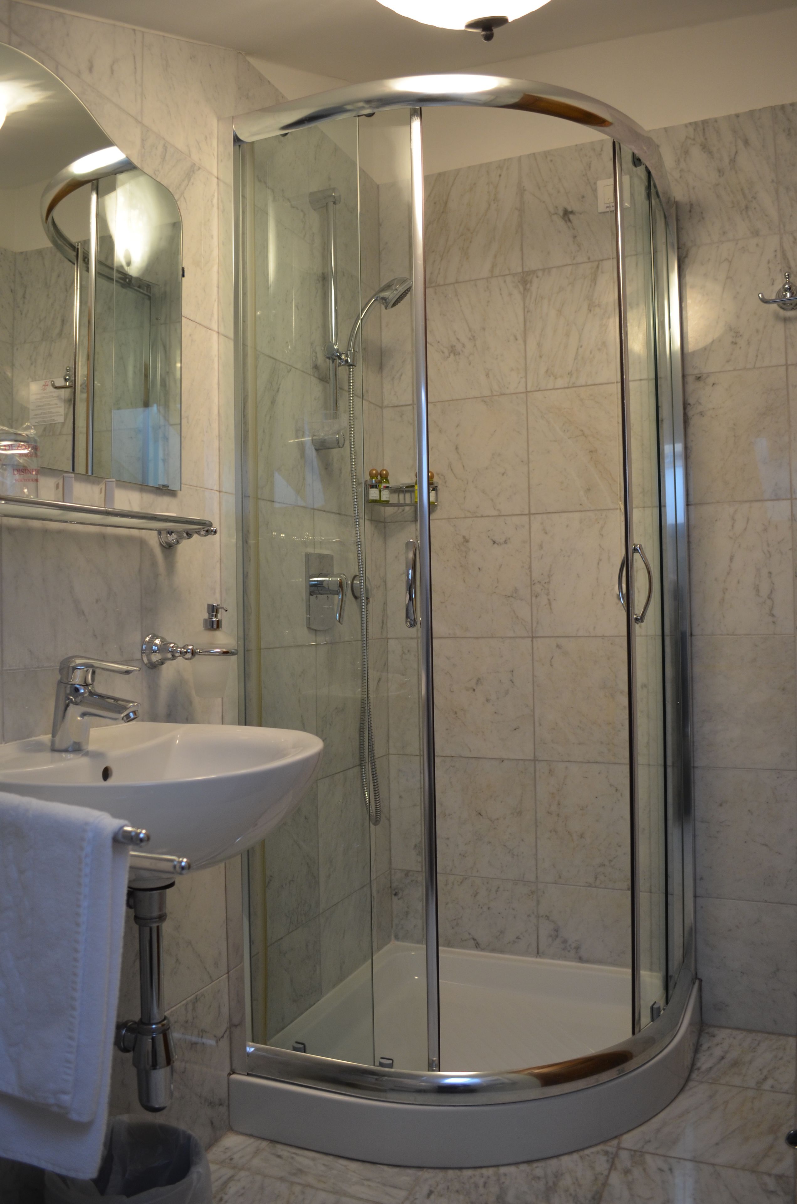 A modern bathroom with a glass-enclosed shower, a white sink, and a mirror above the sink.