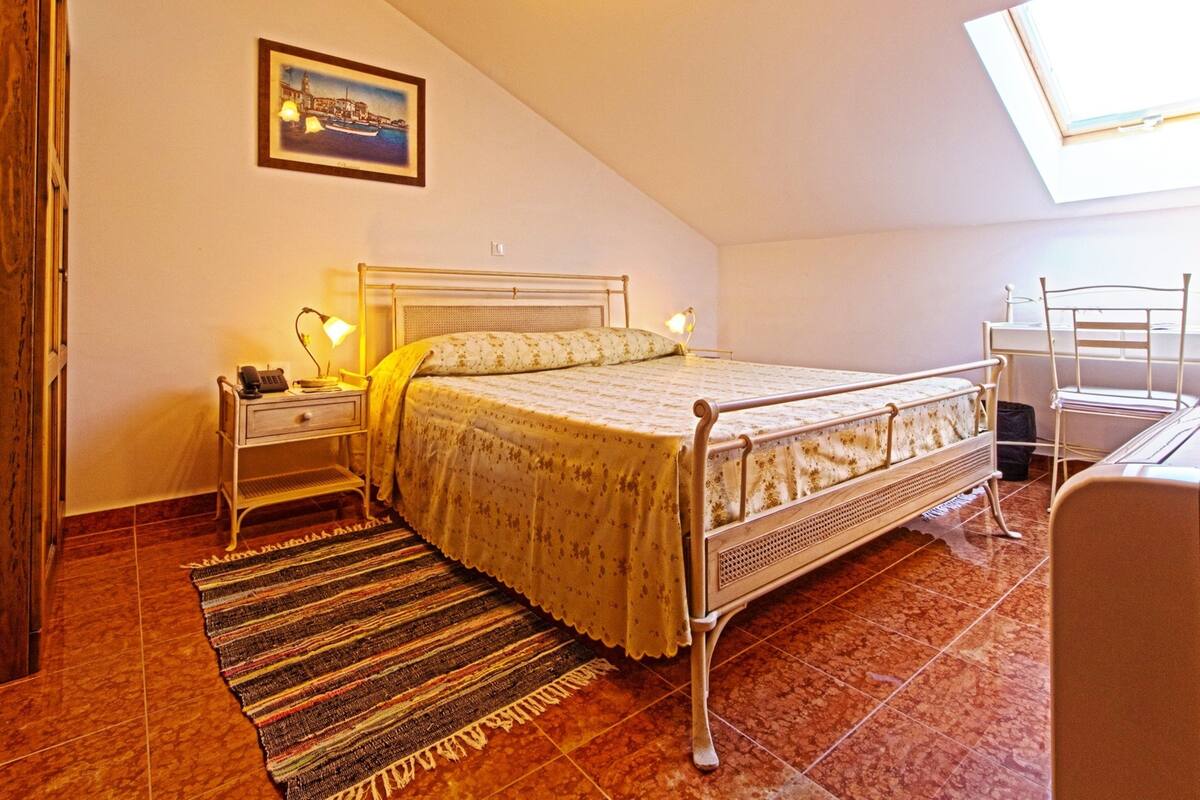 Een slaapkamer met een bed, nachtkastjes, een bureau en een stoel.