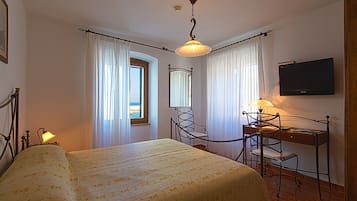Ein Hotelzimmer mit einem Bett, einem Schreibtisch mit Stuhl, einem Fernseher und einem Fenster mit Vorhängen.