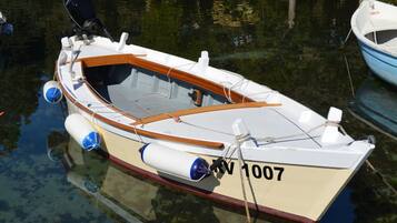 Un pequeño barco a motor con cabina, dos motores fueraborda y el número de registro RV 1007.