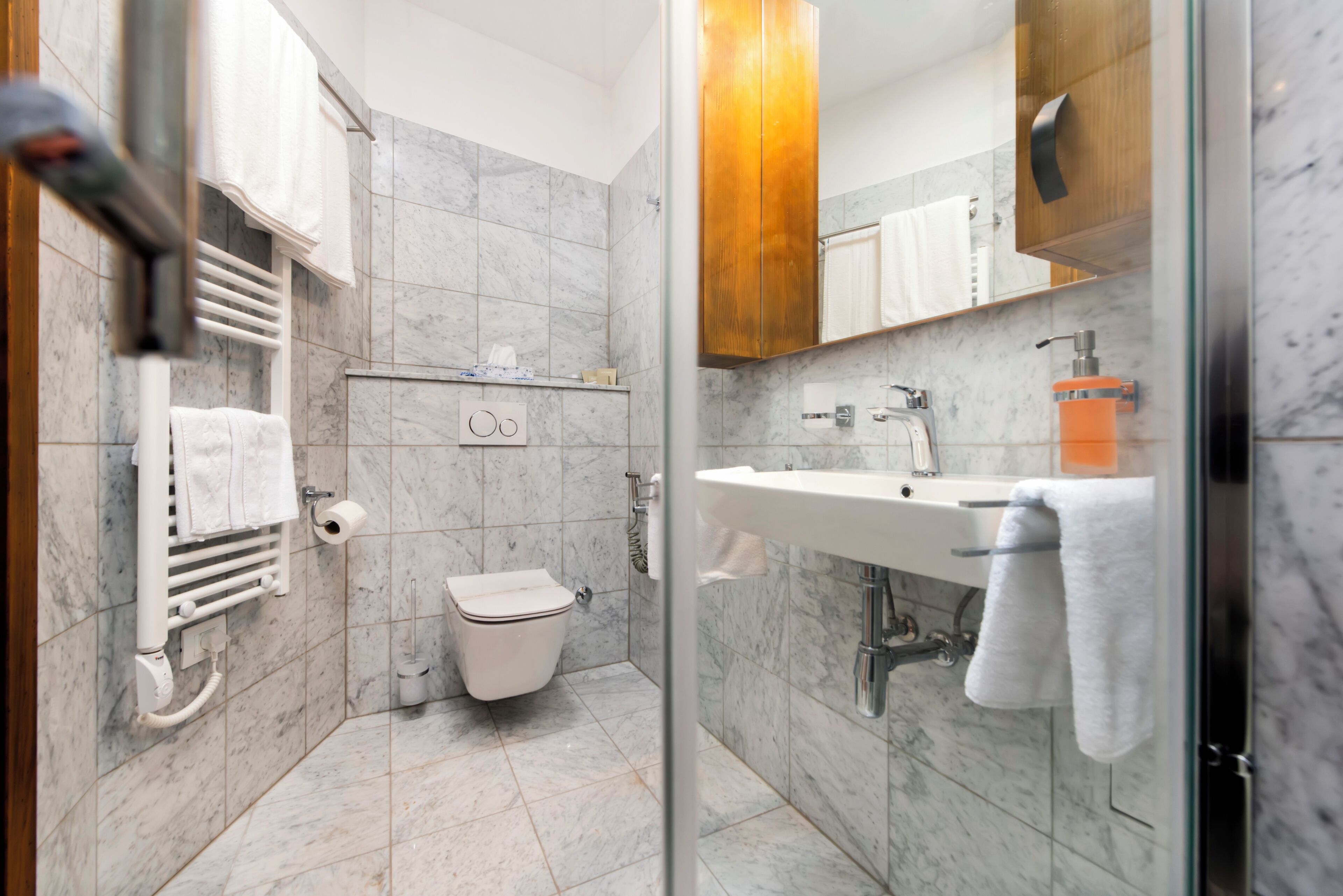 Een moderne badkamer met een glazen douchecabine, toilet, wastafel en spiegel.
