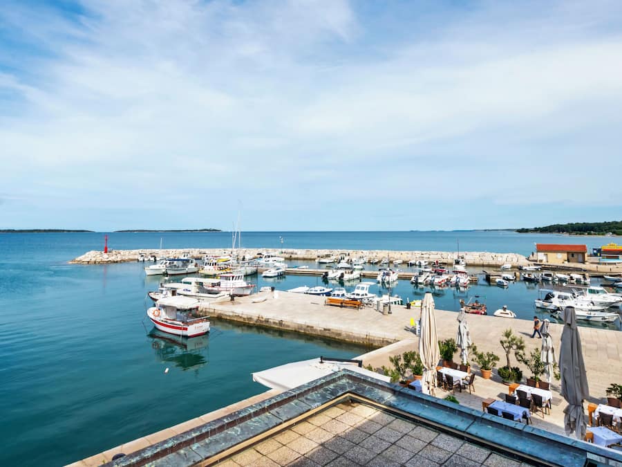 Ein Yachthafen mit vertäuten Booten, eine Mole und ein Restaurant mit Außenbereich.