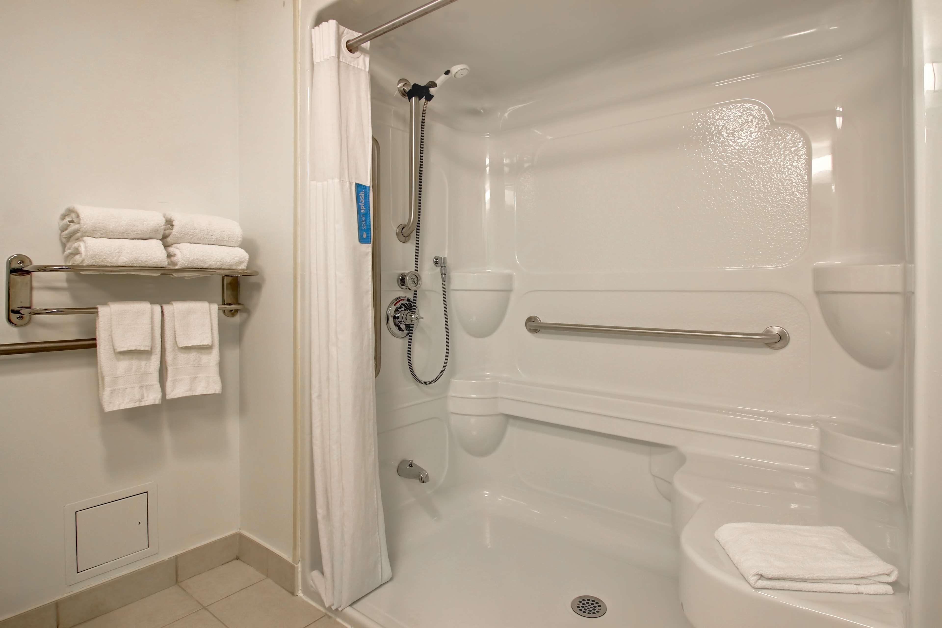 A modern bathroom with a walk-in shower, a toilet, and a towel rack with neatly folded towels.