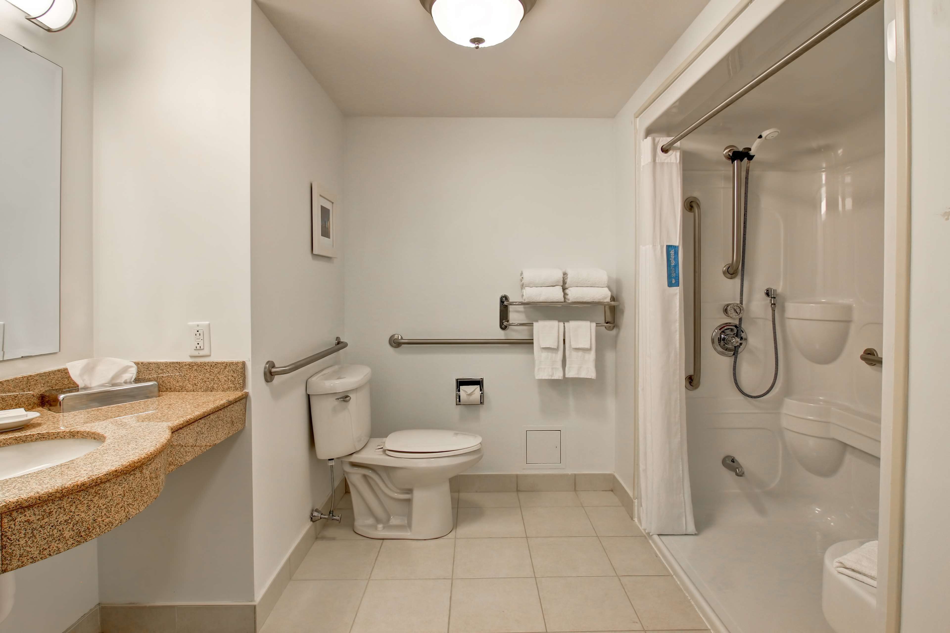 Une salle de bain moderne équipée de toilettes, d’un lavabo et d’un espace douche.