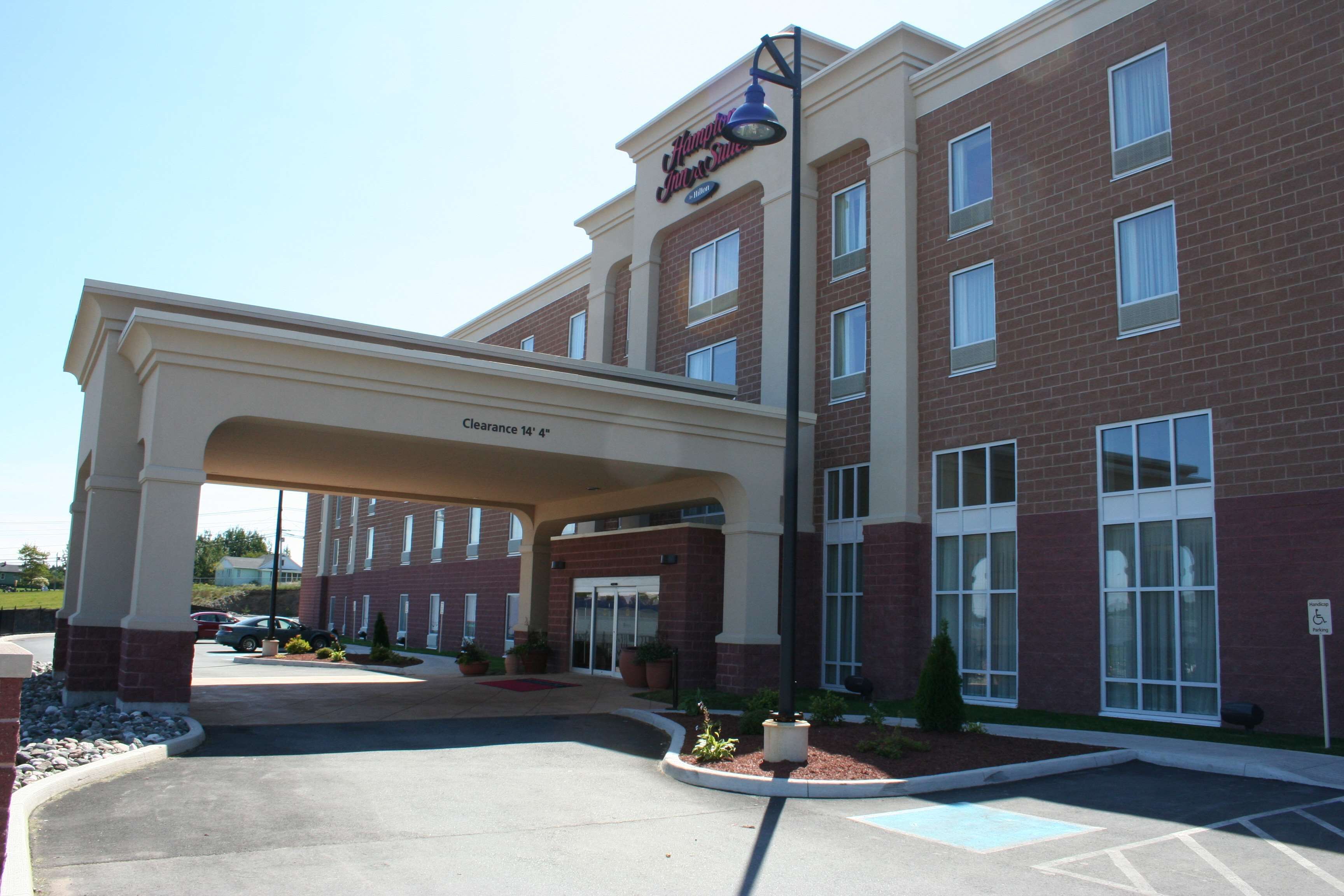 A hotel entrance with a covered walkway, clear signage, and a parking area.