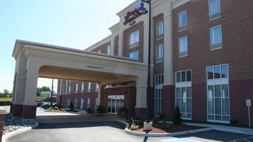 A hotel entrance with a covered walkway, clear signage, and a parking area.