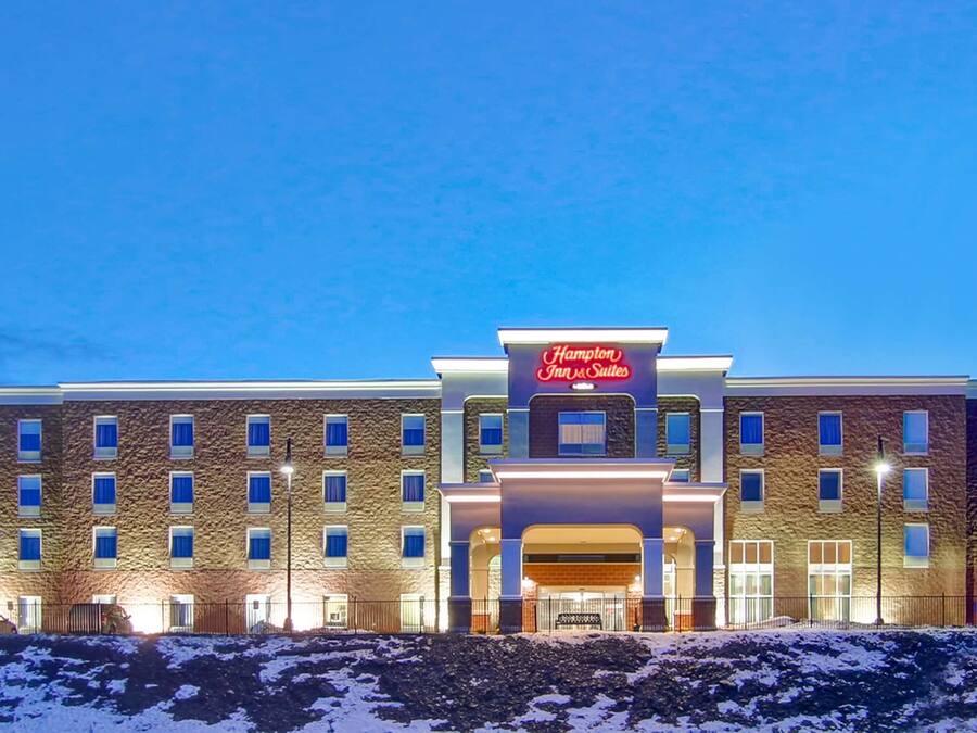 A Hampton Inn & Suites hotel with a brick facade, multiple windows, and a prominent entrance.
