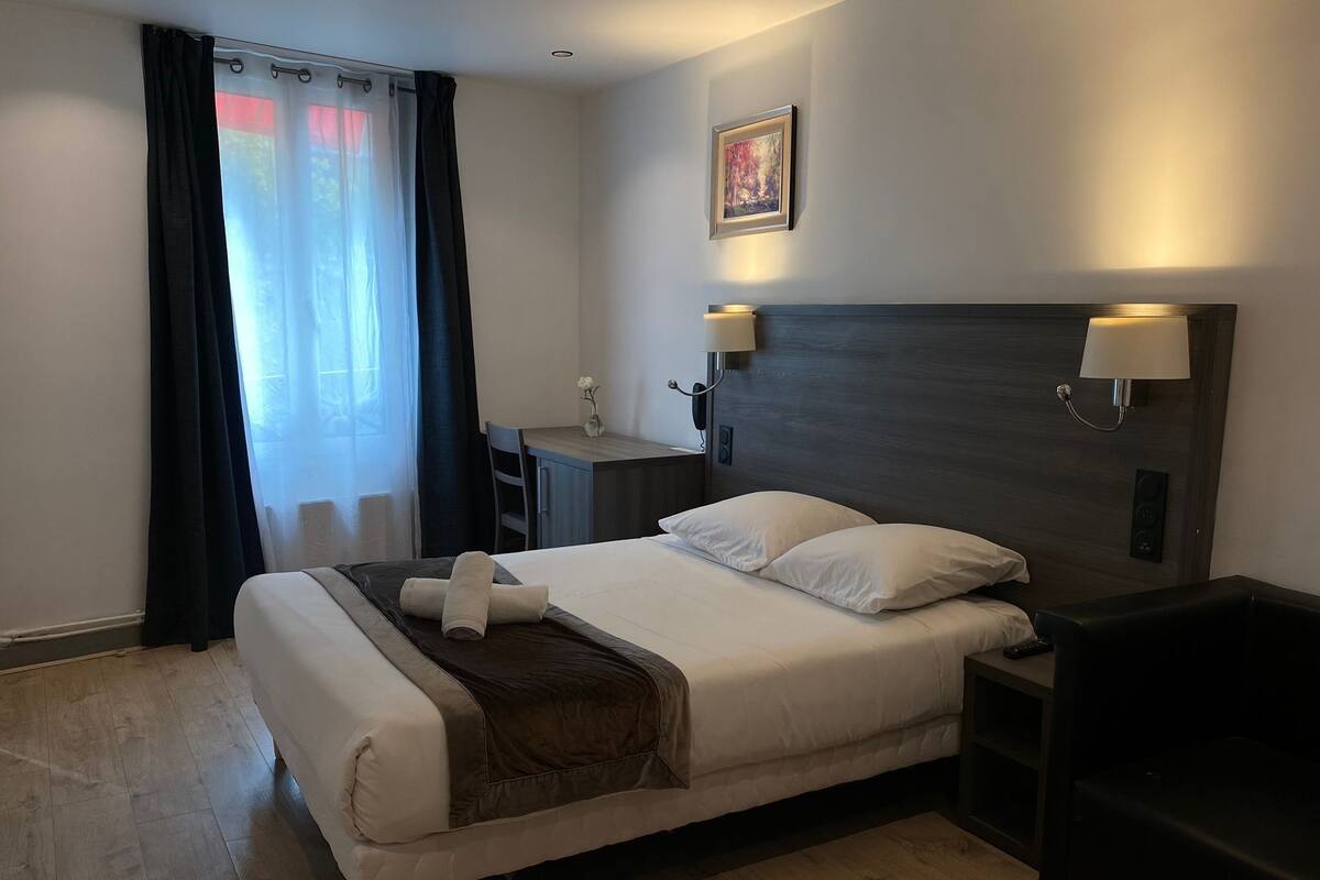Ein Hotelzimmer mit einem Bett, Nachttischen, einem Schreibtisch und einem Bild an der Wand.