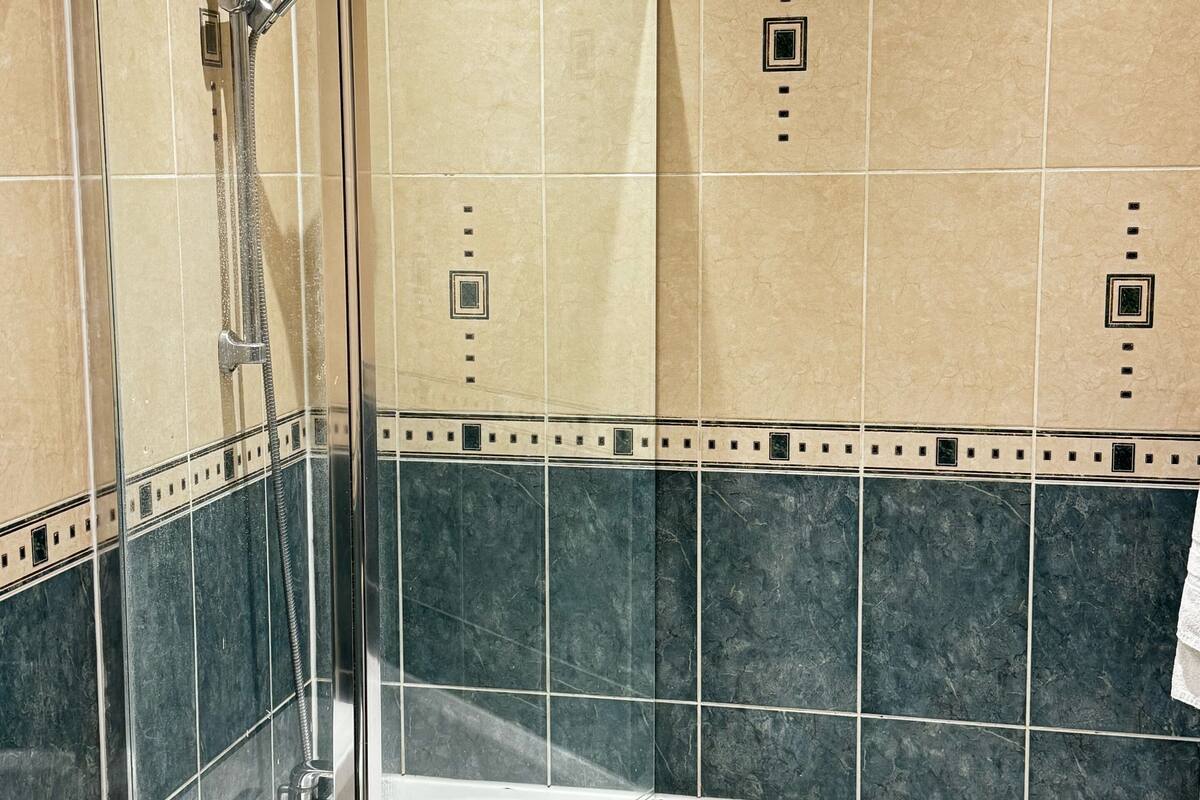 Ein Badezimmer mit Duschkabine aus Glas, einer Badewanne und gefliesten Wänden.