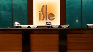 A reception desk with a large illuminated sign reading "Isle" and a digital display. - Isle Casino Hotel Waterloo - A Caesars Rewards Destination (Waterloo)