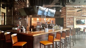A bar area with a long counter, multiple stools, and a kitchen in the background. - Isle Casino Hotel Waterloo - A Caesars Rewards Destination (Waterloo)