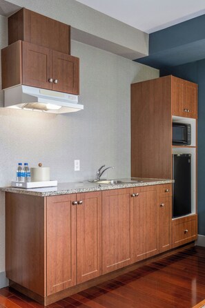 Cocina con armarios de madera, un lavamanos de acero inoxidable y un microondas.