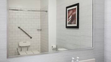 Un baño moderno con un espejo grande, un lavamanos blanco y un cuadro en la pared.