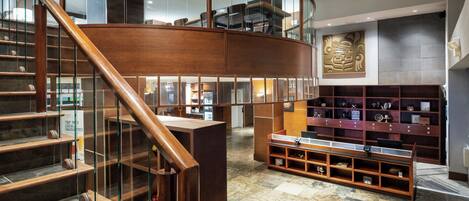 A spacious lobby with a curved wooden staircase, a reception desk, and a display of trophies.