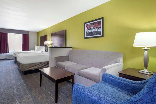 A hotel room with a bed, a sofa, a small table, a lamp, and a picture on the wall. - Best Western Plus Mansfield Inn & Suites (Mansfield)