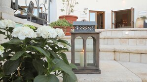 A stone staircase leading to a building entrance, a potted plant with white flowers, and a lantern with a lit candle. - Hotel Brancamaria (Dorgali)