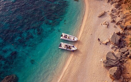 An aerial view of a beach with two boats anchored near the shore.
