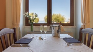 A dining table set with a vase of flowers, two glasses of champagne, and a silver pitcher. - Hotel Brancamaria (Dorgali)