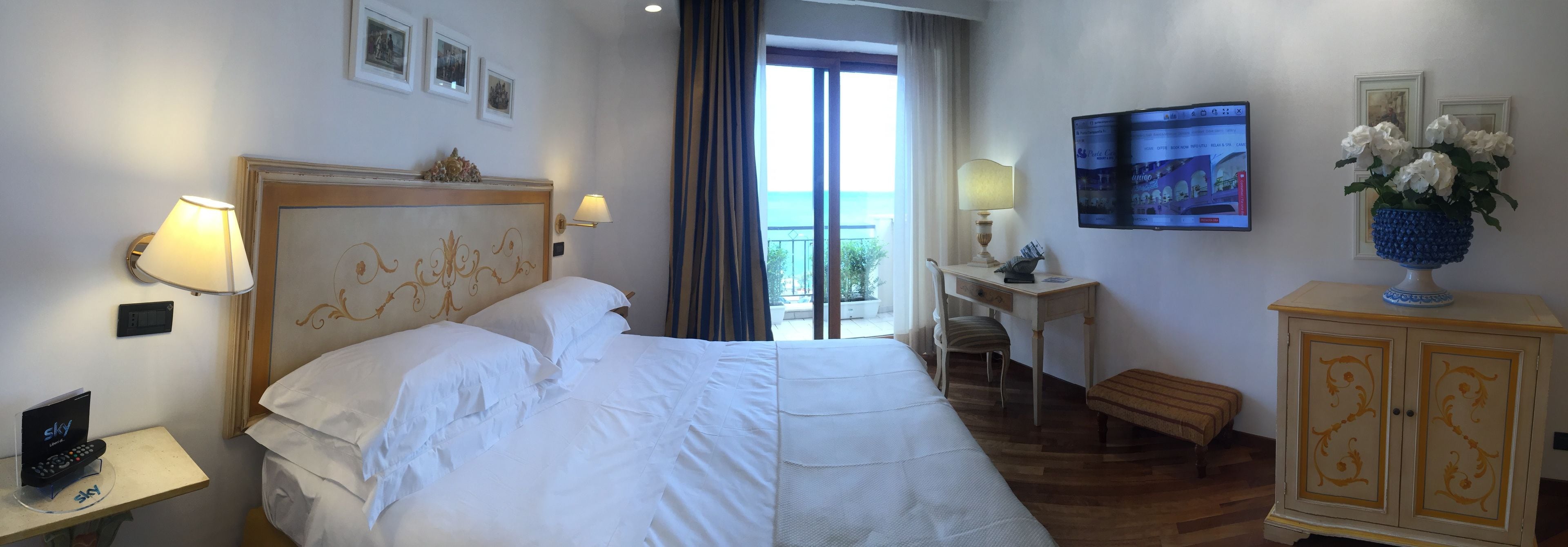 A hotel room with a bed, a desk, a television, and a view of the outdoors.