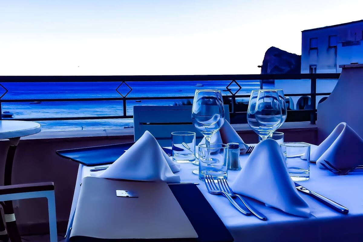 Una tavola apparecchiata per la cena con vista sull'oceano.