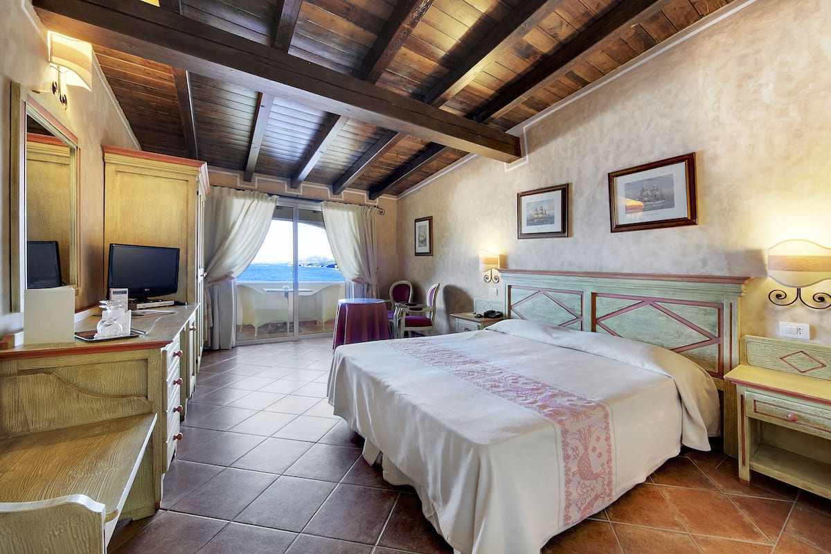 Une chambre d’hôtel avec un lit, un bureau, une chaise et une vue sur la mer.