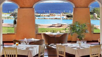 Un ristorante con tavoli all'aperto affacciato su una piscina e il mare.