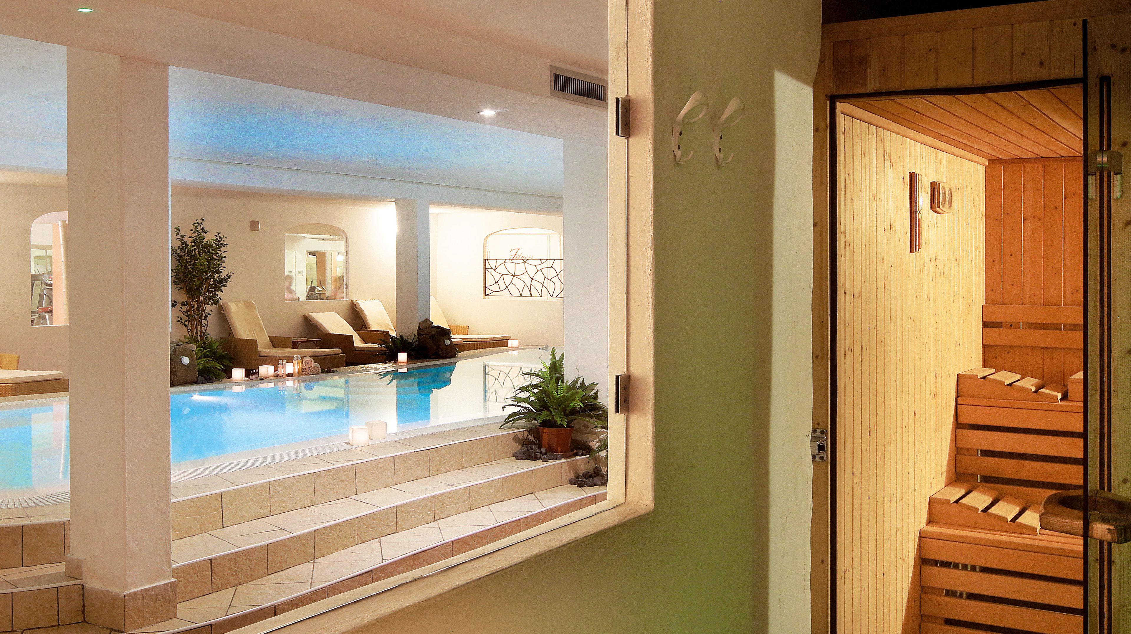 Un área de spa con piscina, sillones reclinables y una sauna de madera.