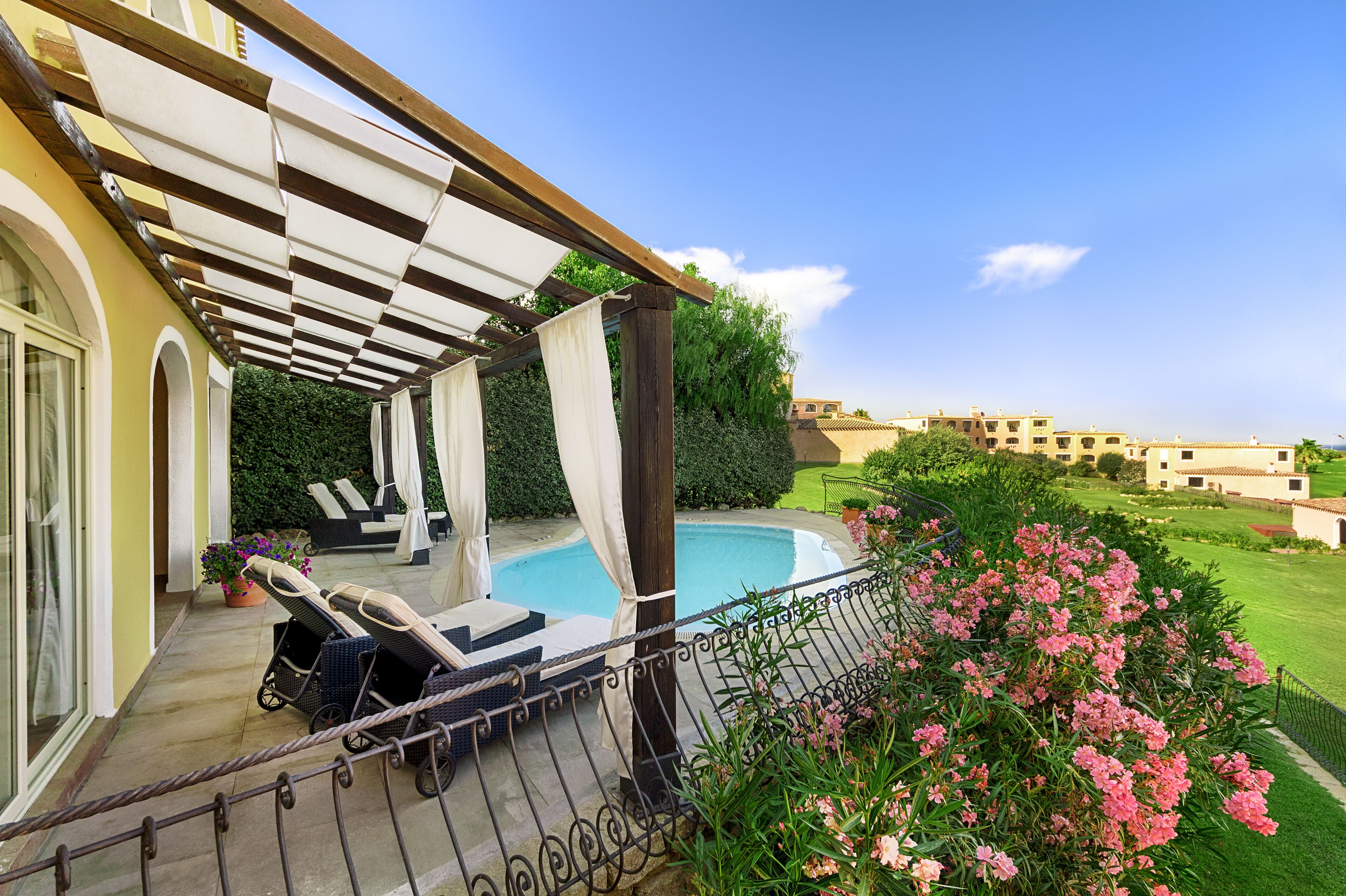 A covered outdoor area with lounge chairs and a pool.