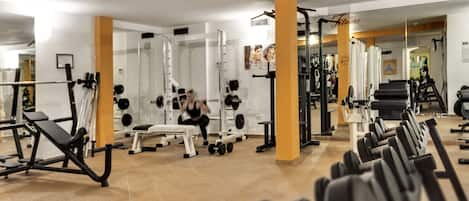 A gym with various exercise equipment, including dumbbells, benches, and weight machines.