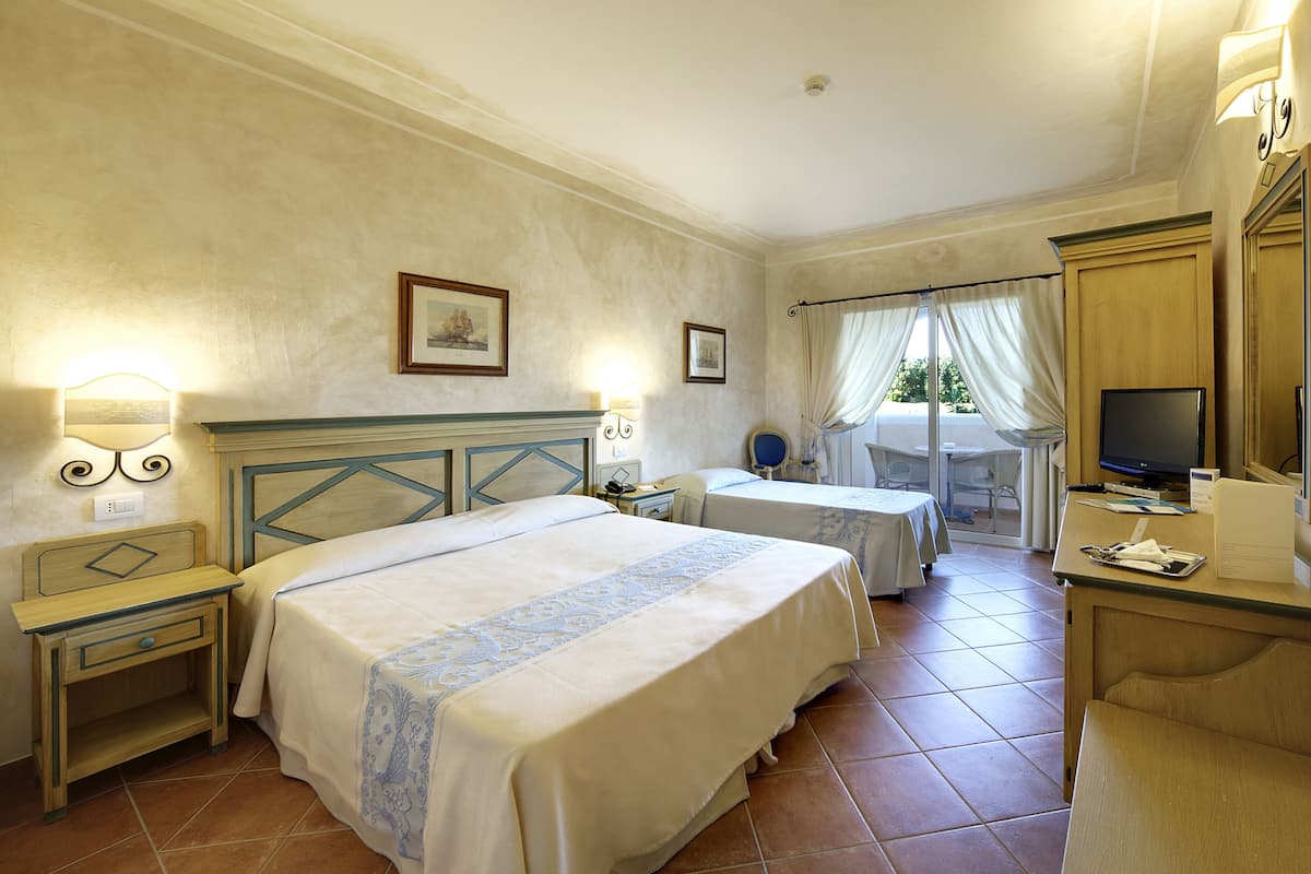 Une chambre d’hôtel avec deux lits, un bureau avec un ordinateur, une télévision et un balcon avec vue.