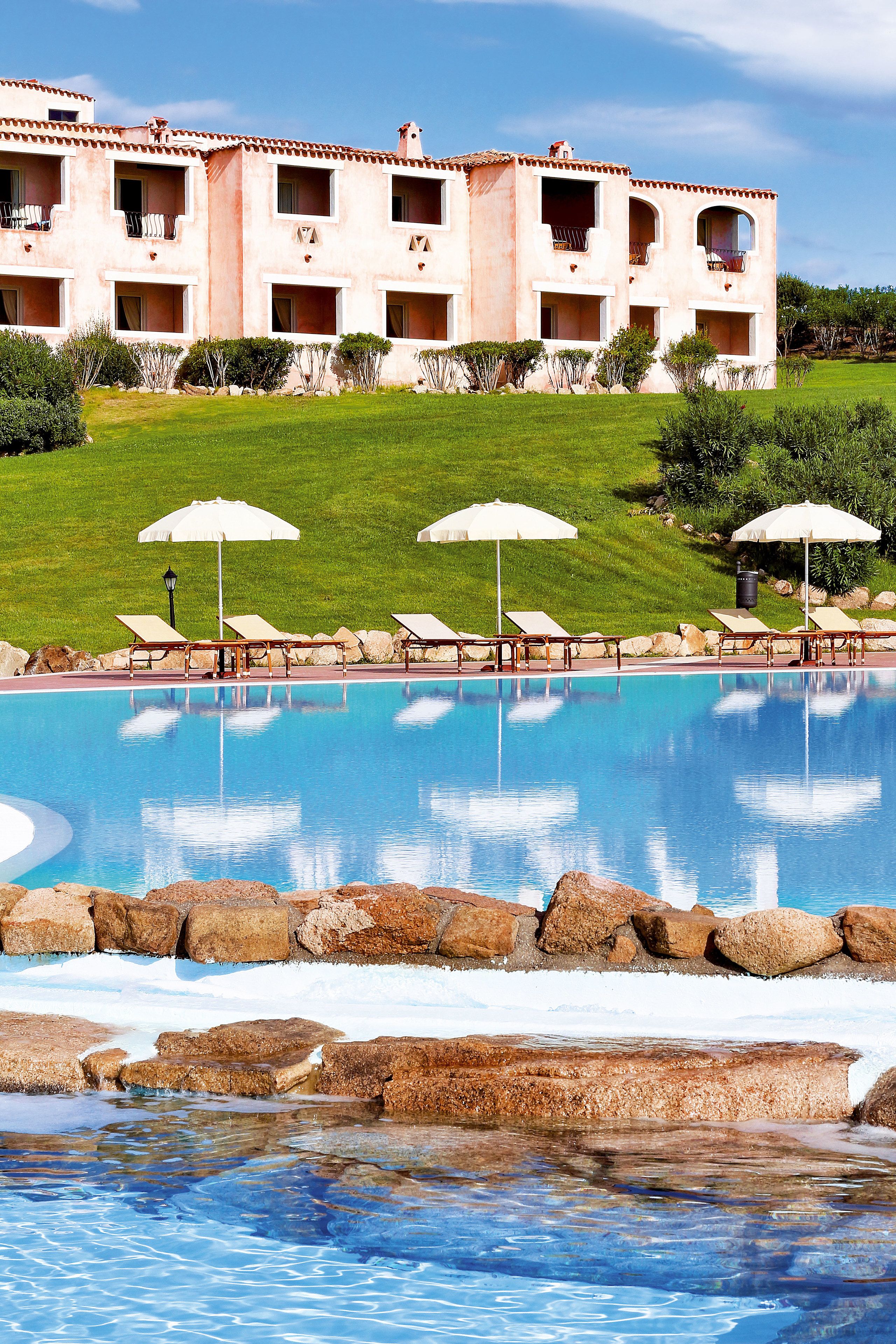 Ein Hotel mit Swimmingpool, Liegestühlen und Sonnenschirmen.