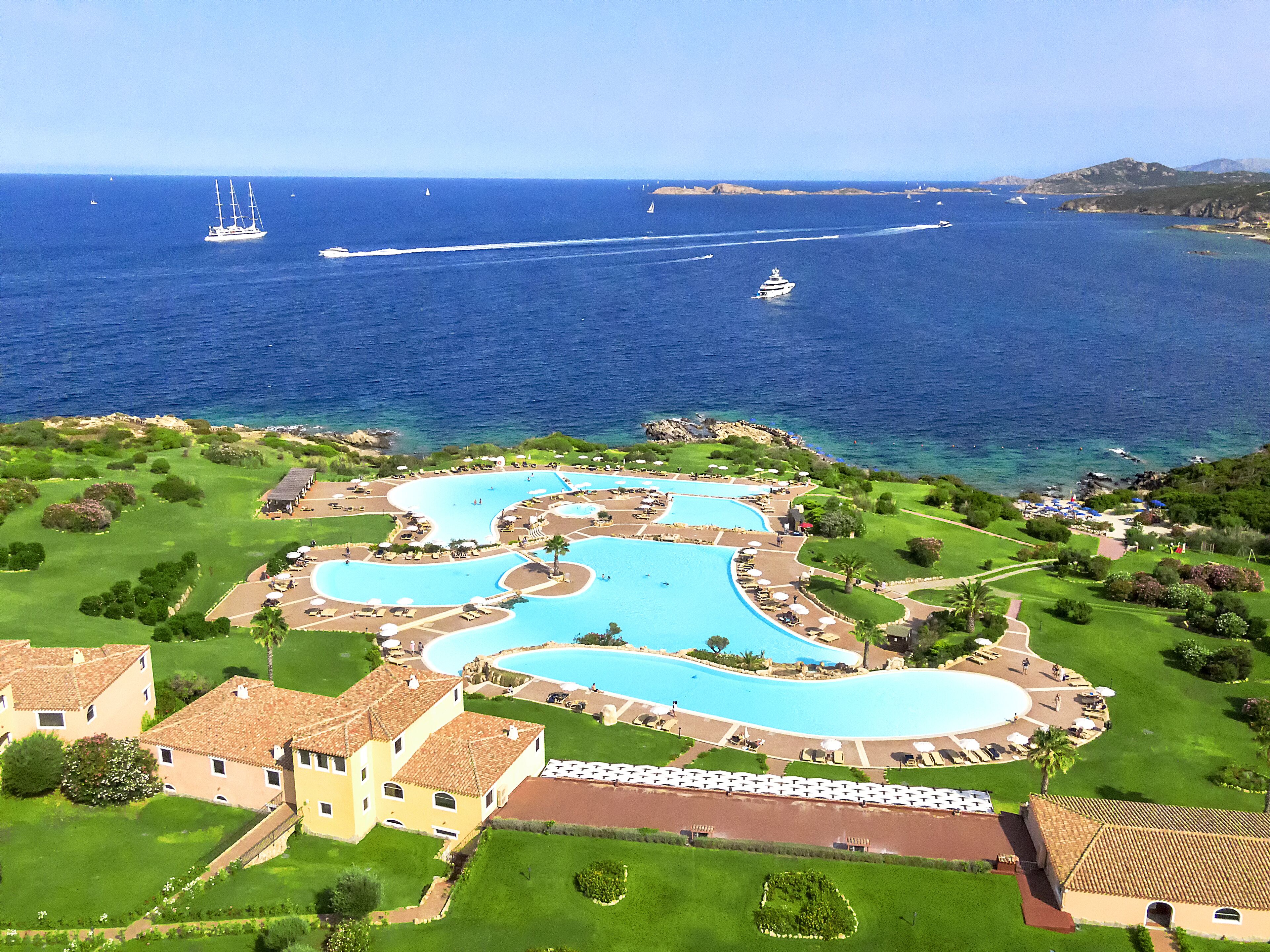 A resort with multiple swimming pools, a golf course, and a view of the sea.