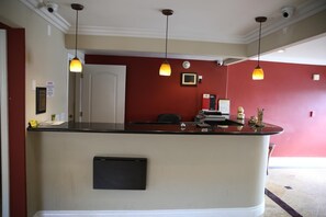 Zona de recepción con mostrador, puerta y tres lámparas colgantes.