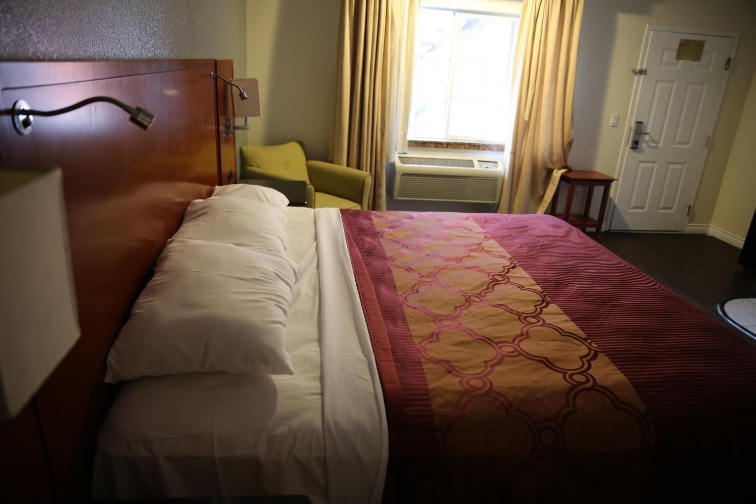 Una camera d'albergo con un letto, una sedia, una scrivania e una finestra con tende.