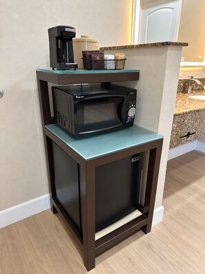 A compact kitchen with a microwave and coffee maker on a small countertop.