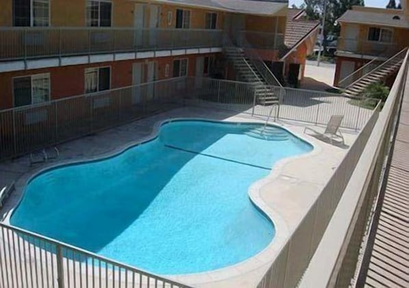 Una piscina de diseño curvo, rodeada por una valla y edificios cercanos.