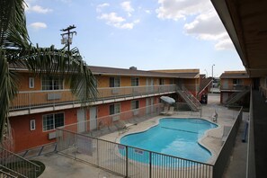 Un motel de varios pisos con piscina, balcones y una escalera que lleva a los pisos superiores.