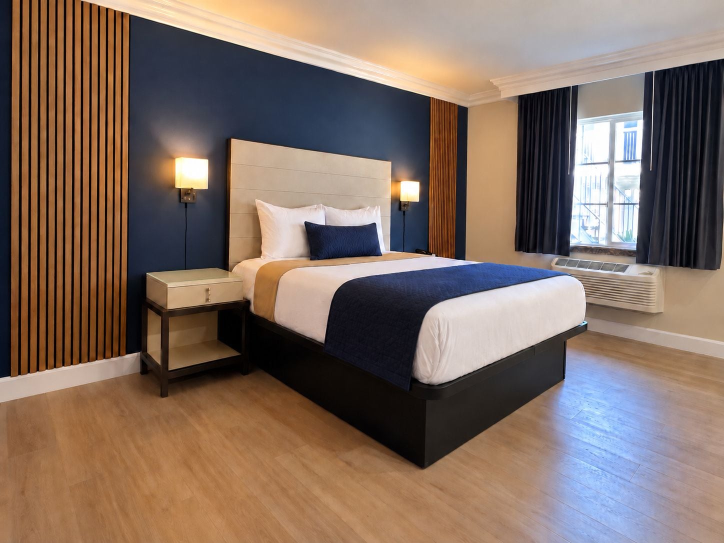 A hotel room with a bed, bedside tables, a wall-mounted lamp, and a window with curtains.