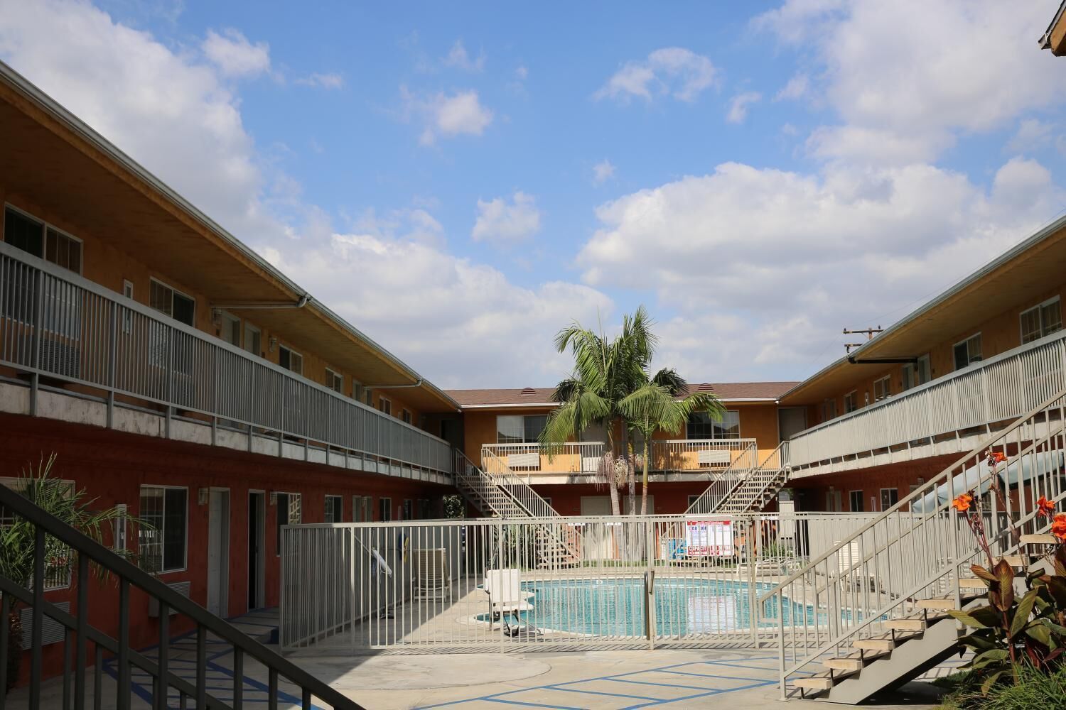 A multi-story building with a central courtyard featuring a swimming pool, surrounded by balconies and staircases.