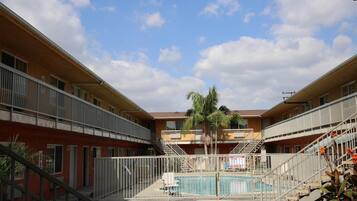 A multi-story building with a central courtyard featuring a swimming pool, surrounded by balconies and staircases.