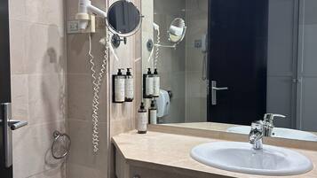 A modern bathroom with two sinks, a bidet, a hairdryer, and a mirror.