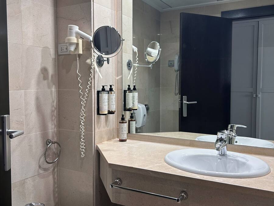 A modern bathroom with two sinks, a bidet, a hairdryer, and a mirror.