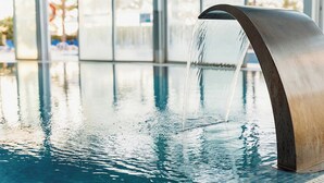 A modern indoor pool with a sleek, metallic water feature. - Senator Águilas Hotel (Aguilas)
