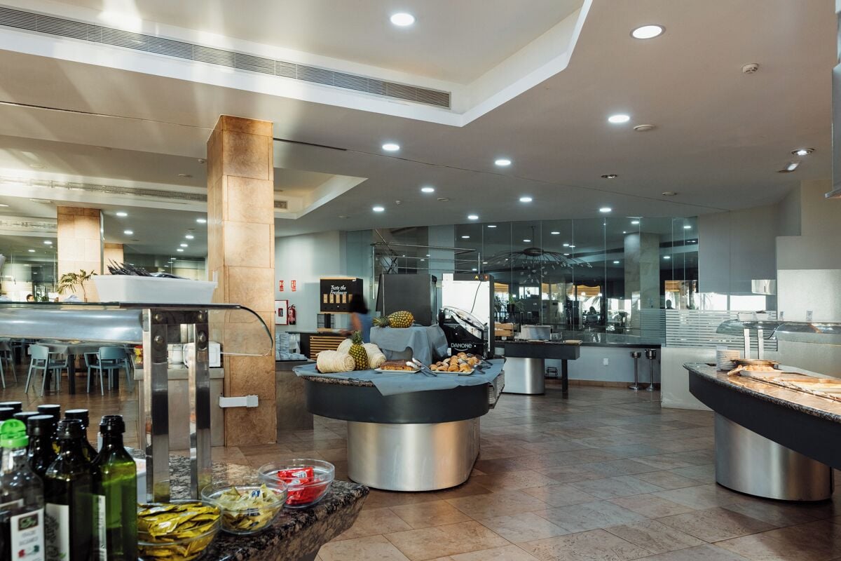 A modern hotel lobby with a buffet area featuring various food items and a bar.