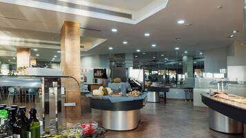 A modern hotel lobby with a buffet area featuring various food items and a bar.