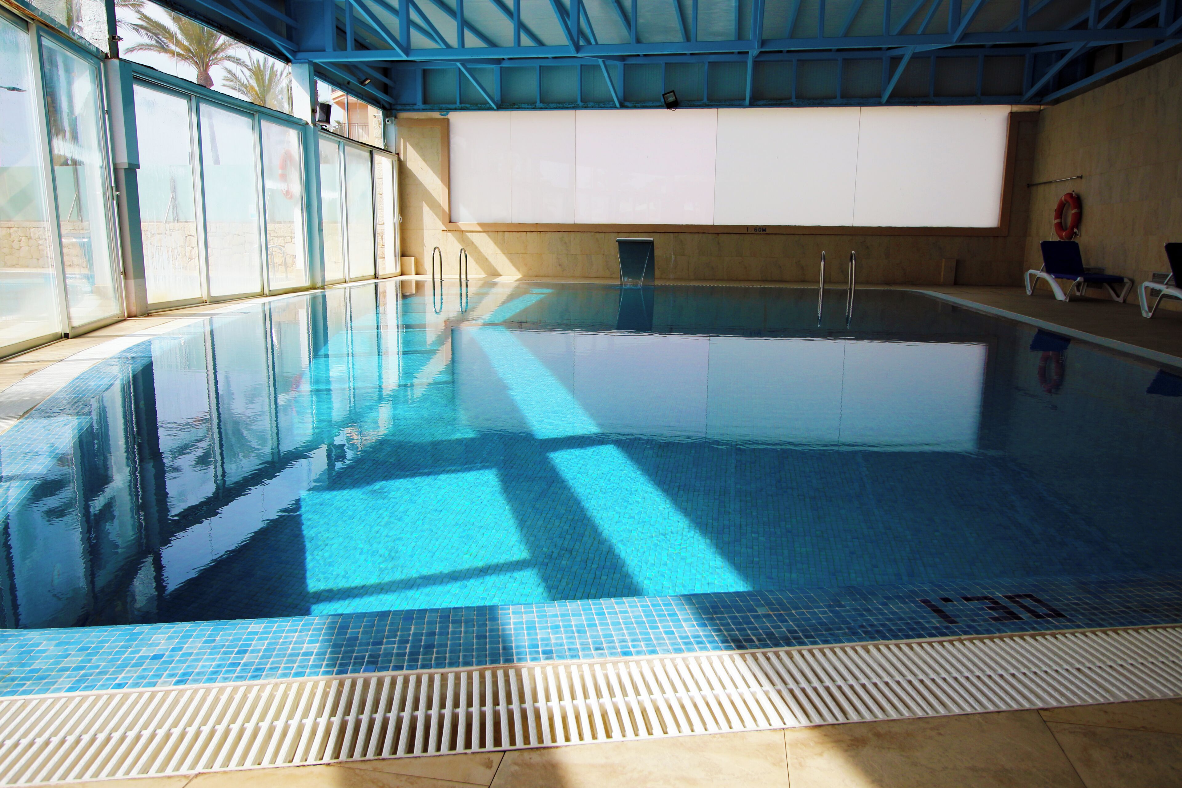 Una piscina interior con agua cristalina, suelo de baldosas y un desagüe en la parte inferior.