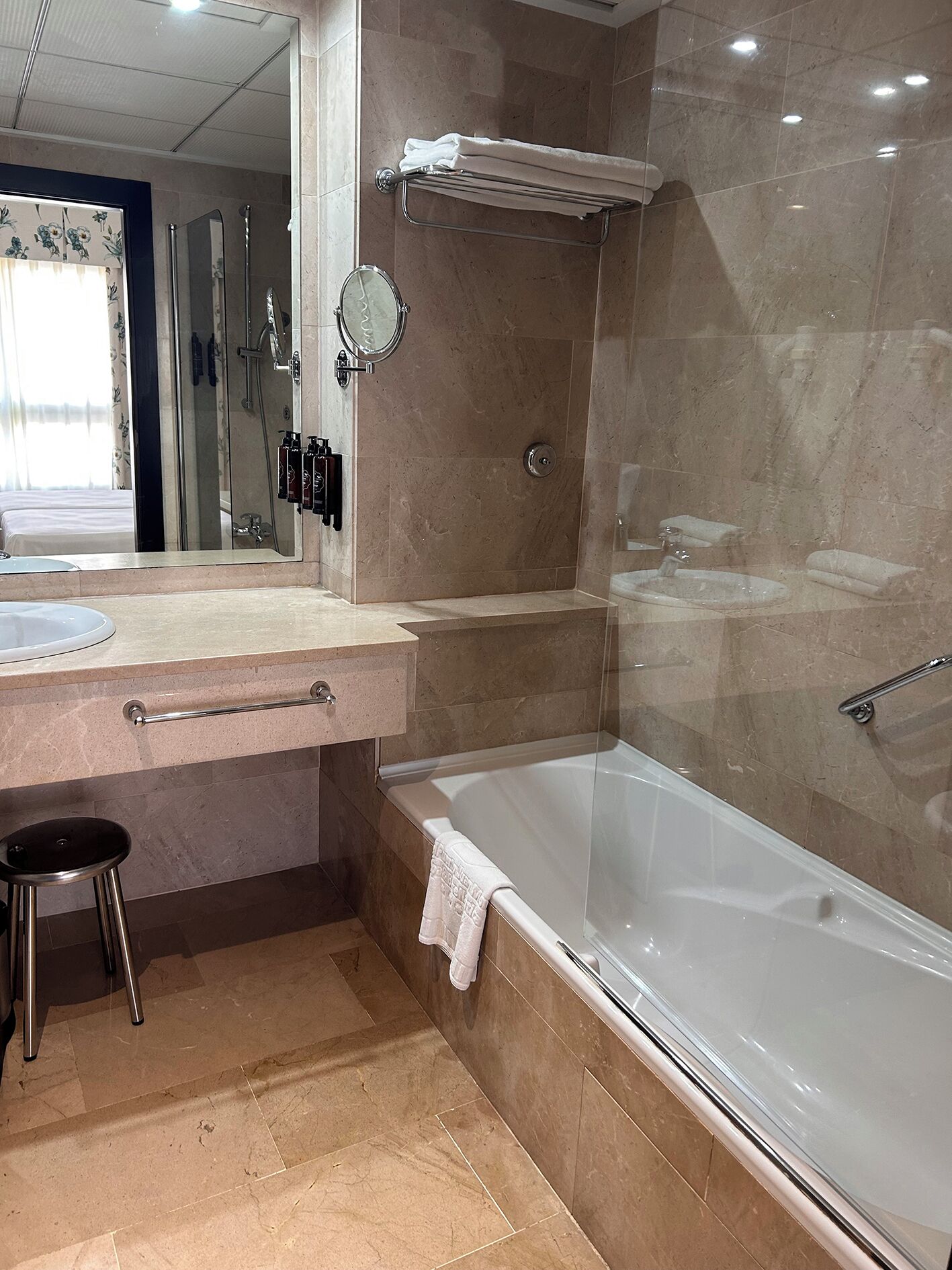 A modern bathroom with a bathtub, a sink, a mirror, and a towel rack.