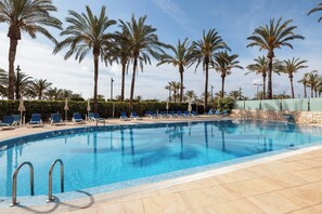 A swimming pool with clear blue water, surrounded by palm trees and lounge chairs. - Senator Águilas Hotel (Aguilas)