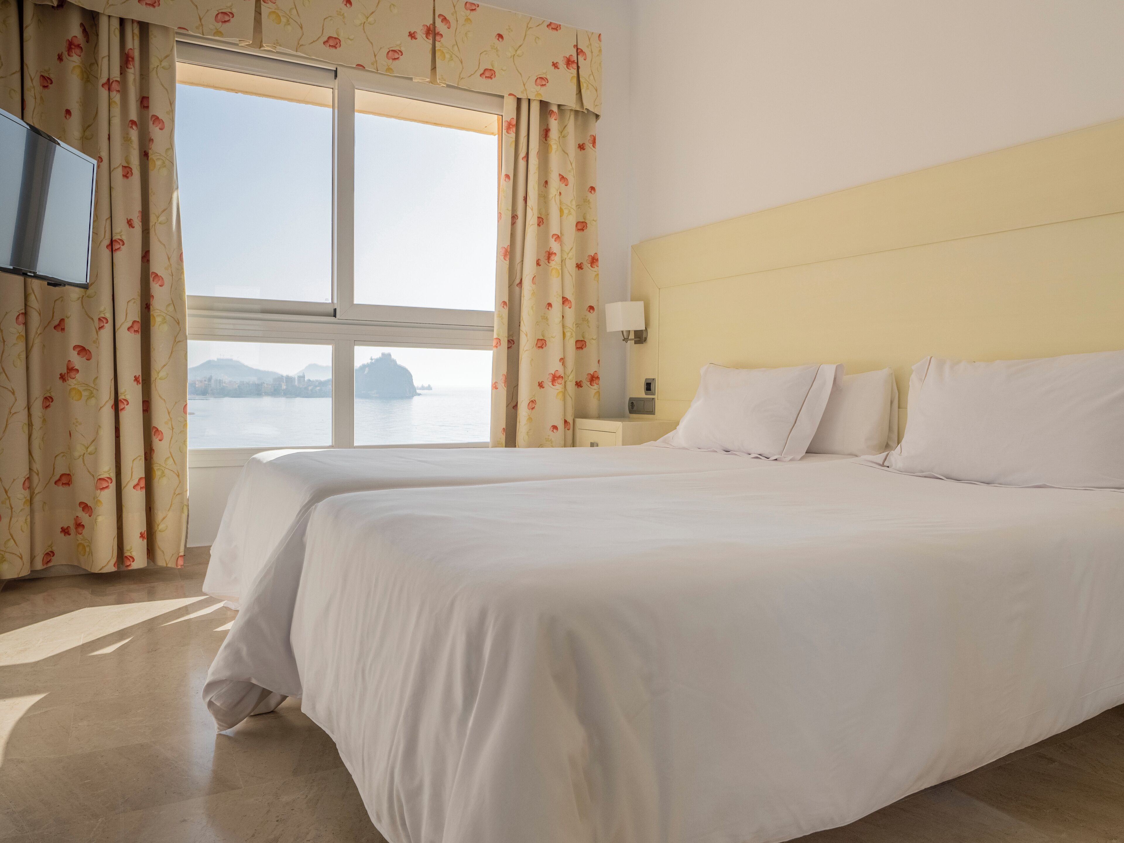 Una habitación de hotel con una cama grande, un televisor y vista a un cuerpo de agua.