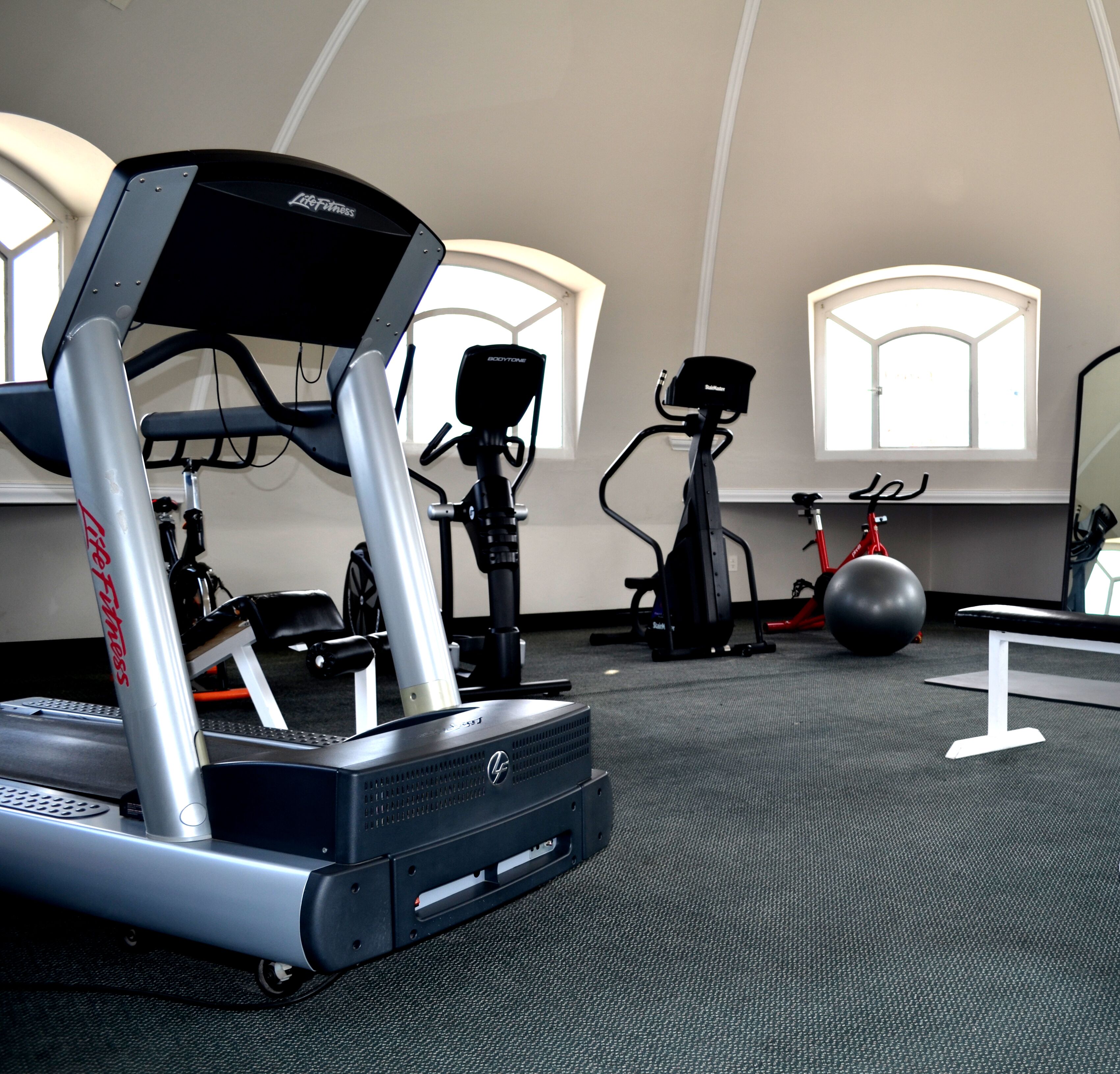 A gym with exercise equipment including a treadmill, stationary bike, and elliptical machine.